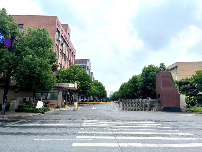 Industrial-site entrance with buildings, trees and an access gate
