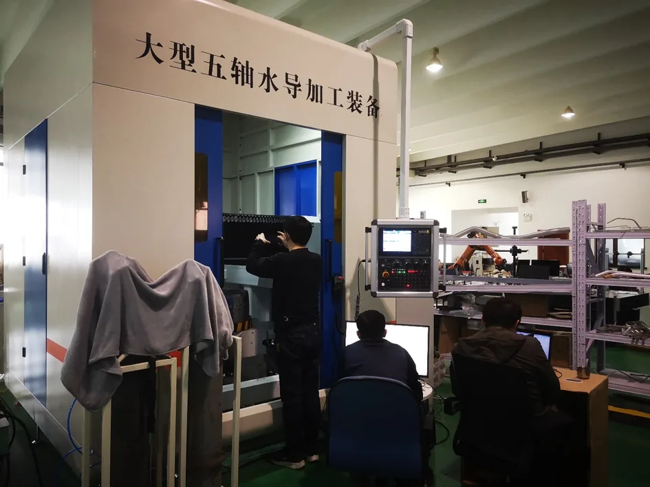 Technicians beside equipment labelled for large five-axis water-guided processing