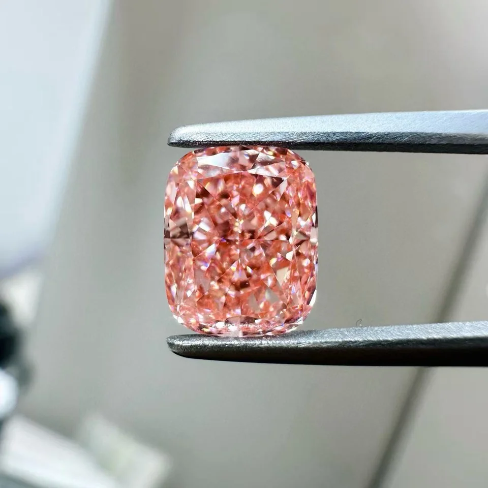 Pink cushion-shaped diamond held in tweezers