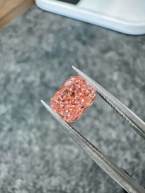 Pink rectangular diamond held in tweezers, supplied photograph